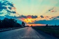 Highway with cars traveling on the sunset. Horizon line with the sun and storm clouds. Journeys. Selective focus Royalty Free Stock Photo