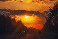 Highway with cars traveling on the sunset. Horizon line with the sun and storm clouds. Journeys. Selective focus Royalty Free Stock Photo