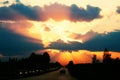 Highway with cars traveling on the sunset. Horizon line with the sun and storm clouds. Journeys. Selective focus Royalty Free Stock Photo