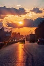 Highway with cars traveling on the sunset. Horizon line with the sun and storm clouds. Journeys. Selective focus Royalty Free Stock Photo