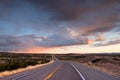 Highway curving into the distance through the landscape near Santa Fe, New Mexico underneath a dramatic colorful sky at sunset Royalty Free Stock Photo