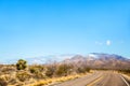 Highway through a desert landscape with mountains and green foliage