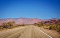 Highway through a desert landscape with mountains and green foliage