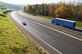 The highway between deciduous forests with leaves in fall colors, the highway goes blue truck and a passenger car Royalty Free Stock Photo