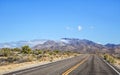 Highway through a desert landscape with mountains and green foliage