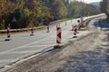 Highway in the forest during repair on an autumn day: half of the road is blocked, warning signs are installed Royalty Free Stock Photo