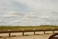Highway guardrail and fence with open landscape and cloudy sky in background Royalty Free Stock Photo