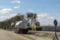 Highway intercity new road construction site with many heavy machinery steamroller, water tanker truck and paver tractor