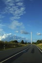 Highway leading to three wind wheels against the blue sky with w Royalty Free Stock Photo