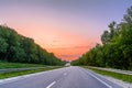 Highway in the middle of the forest belt at sunset Royalty Free Stock Photo