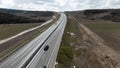 Highway outside the city, panoramic view from above with driving cars. Shot. Straight highway stretching along fields Royalty Free Stock Photo