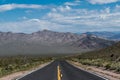 A highway receding to perspective toward a mountain range in a desert landscape