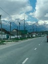 Highway to the left of the house and mountains as well as the sky with white clouds
