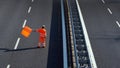 A highway worker with a high visibility work suit waves the orange flag to slow down traffic before the roadblock Royalty Free Stock Photo