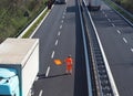 A highway worker with a high visibility work suit waves the orange flag to slow down traffic before the roadblock Royalty Free Stock Photo