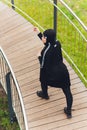 Hijab girl exercising on walkway bridge in early morning. Muslim woman wearing sports clothes doing stretching workout Royalty Free Stock Photo