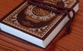 Hijri Islamic New Year concept. Close up closed holy Quran and rosary on a desk