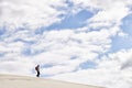 Hike, dunes and sky with male person in nature for adventure, walk and desert landscape with clouds. Fitness, travel and Royalty Free Stock Photo