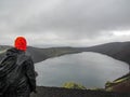 Hiker adventurer hiking in raincoat back standing outdoor looking crater lake in Laugaveur trek in stunning nature landscape,