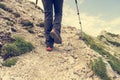 Hiker ascending a mountain and walking path upwards using poles.