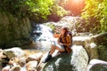 Hiker asian woman drinking water after look binoculars in the water fall, background forest