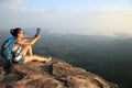 Hiker asian woman using digital tablet taking photo at mountain peak cliff Royalty Free Stock Photo