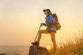 Hiker asian women walking in national park with backpack. Woman tourist going camping in meadow forest, sunset background.