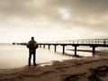 Hiker with backpack alone on sandy beach, sunrise above sea bridge. Royalty Free Stock Photo