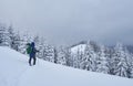 Hiker, with backpack, is climbing on the mountain range, and admires snow-capped peak. Epic adventure in the winter Royalty Free Stock Photo