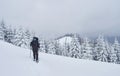 Hiker, with backpack, is climbing on the mountain range, and admires snow-capped peak. Epic adventure in the winter Royalty Free Stock Photo