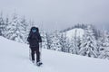 Hiker, with backpack, is climbing on the mountain range, and admires snow-capped peak. Epic adventure in the winter Royalty Free Stock Photo