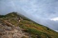 Hiker with backpack going uphill. Hiker going up to the mountain peak on a very steep trail Royalty Free Stock Photo