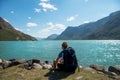 hiker with backpack sitting and looking at Gjende lake in Jotunheimen National