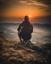 Hiker with backpack sitting on mountain and enjoying sunset