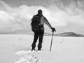 Hiker with backpack snowshoeing in deep drift. Man with walk in hill.