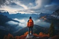 Hiker with backpack standing on the edge of a cliff and enjoying the view of Dolomites, Italy, rear view of Sporty man on the Royalty Free Stock Photo