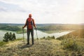 Hiker with backpack standing on a top of mountain and enjoying the beautiful view of valley Royalty Free Stock Photo