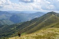 Hiker with backpack standing on a top of a mountain enjoying lookout view of mountains. Nature landscape in Carpathians