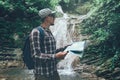 Hiker With Backpack Is Standing By Waterfall And Looks At The Map Holidays And Tourism Concept Royalty Free Stock Photo