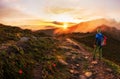 Hiker with backpack walking along a mountain trail in the background of dawn Royalty Free Stock Photo