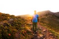 Hiker with backpack walking along a mountain trail in the background of dawn Royalty Free Stock Photo