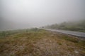 Hiker with backpack walking on a foggy morning road