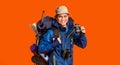 Hiker with binoculars smiling over orange background