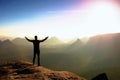 Hiker in black. Gesture of triumph. Tall tourist on the peak of sandstone rock in national park Saxony Switzerland watching into m