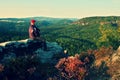 Hiker in black with red baseball cap on sharp cliff and watch to valley. Colorful summer day. Royalty Free Stock Photo