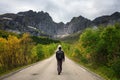 Hiker walks on a scenic road on Lofoten islands in Norway