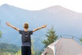 Hiker child boy standing near a tent in mountain campsite with raised hands enjoying view of nature Royalty Free Stock Photo