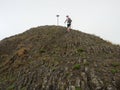 Hiker climbing on sharp peak of basalt formation of volcano Royalty Free Stock Photo
