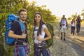 Hiker couple with backpacks in nature. A group of friends are hiking the route along the road in the countryside.