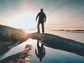 Hiker in dark sportswear with poles and sporty backpack. Coastline trail on rocky shore. Alone tourist enjoy Royalty Free Stock Photo